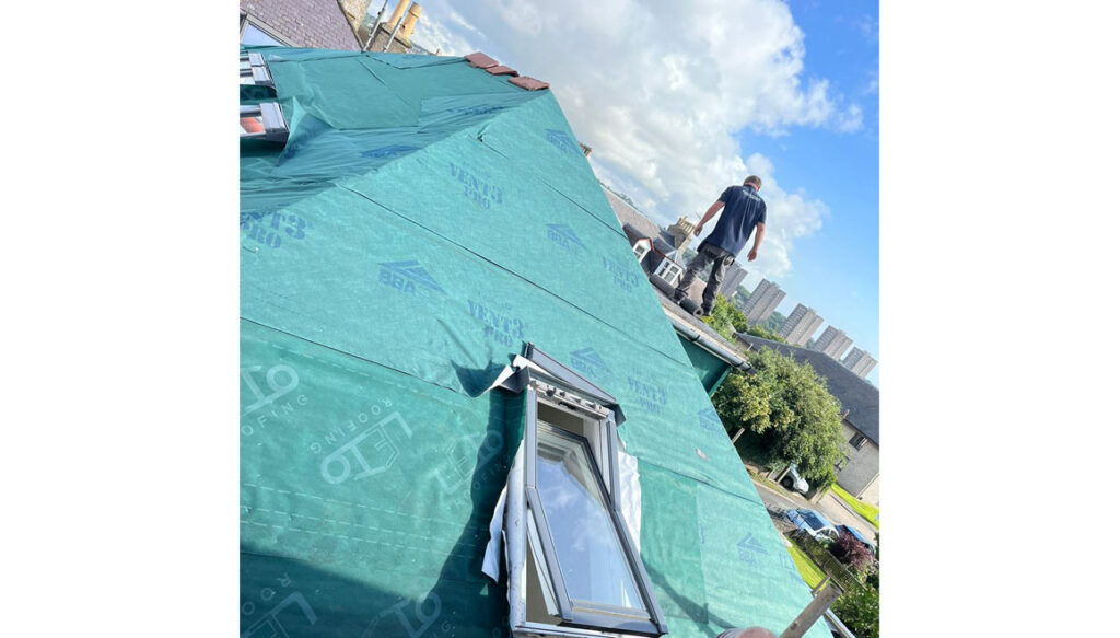 Man working at height fixing slated roof and Velux windows
