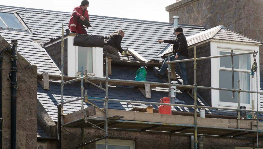 Men working at high on scaffolding fitting new slate roof
