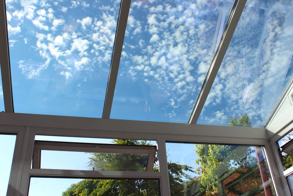 Photo showing a glass conservatory roof with panels of self-cleaning glass. This glass is slightly tinted and has special properties, helping to reflect the outside heat in the summer and retain the interior heat in the winter.